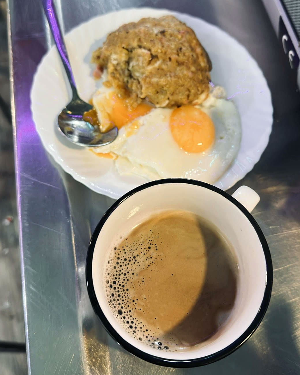 Bolón de verde con dos huevos fritos y un café, servidos en la barra