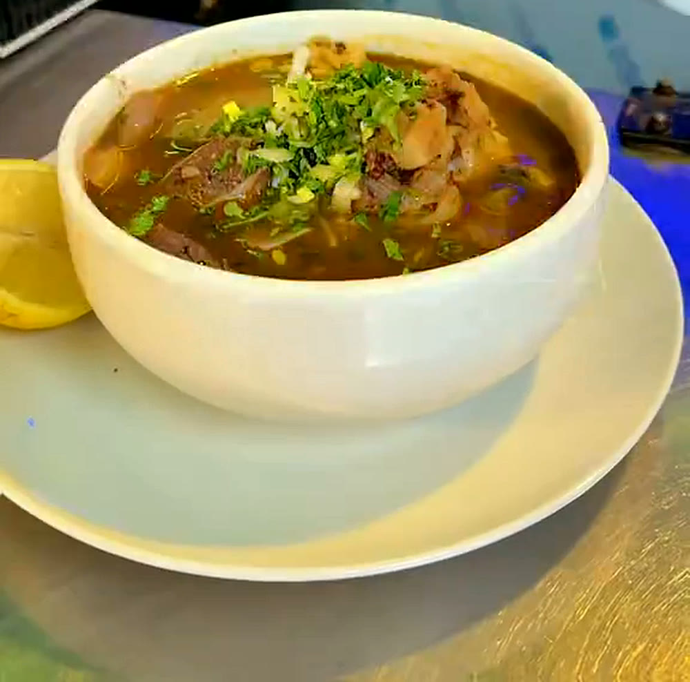 Cuenco de caldo con carne y cilantro, con limón, en la barra del bar